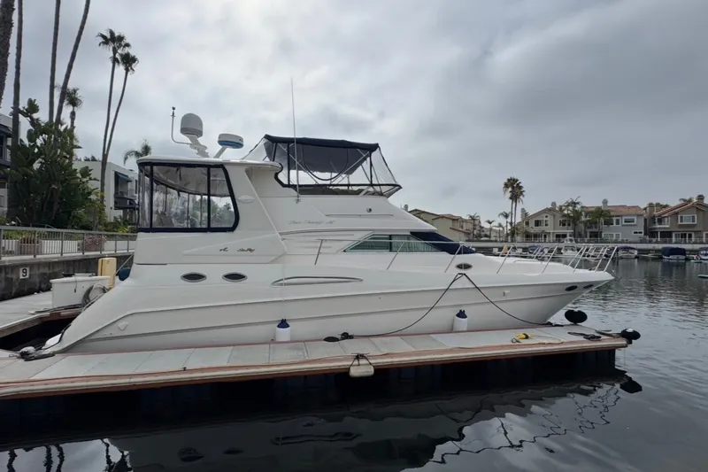 The Image of 1997 Sea Ray 420 Aft Cabin yacht docked in a marina, surrounded by palm trees. - 0