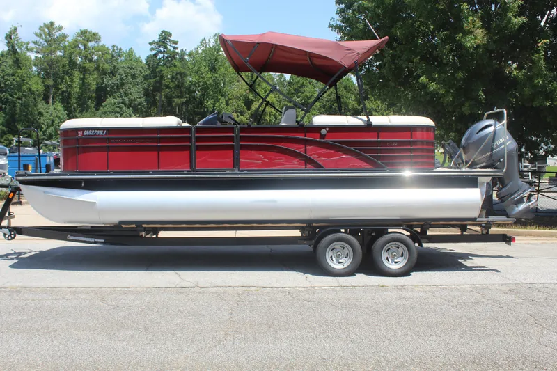 The Image of A red 2016 Bennington 2250GSR pontoon boat on a trailer, featuring a canopy and outboard motor. - 1