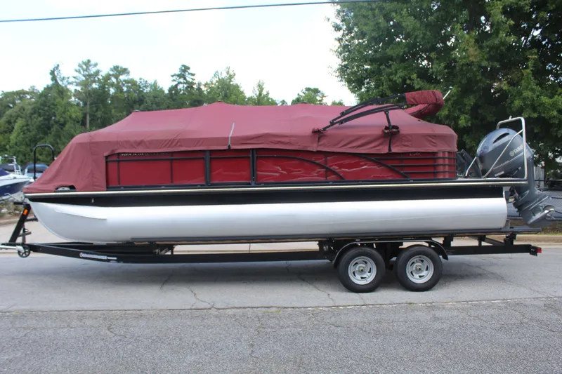 Slide: The Image of A 2016 Bennington 2250GSR pontoon boat on a trailer, featuring red covers and an outboard motor. - 17