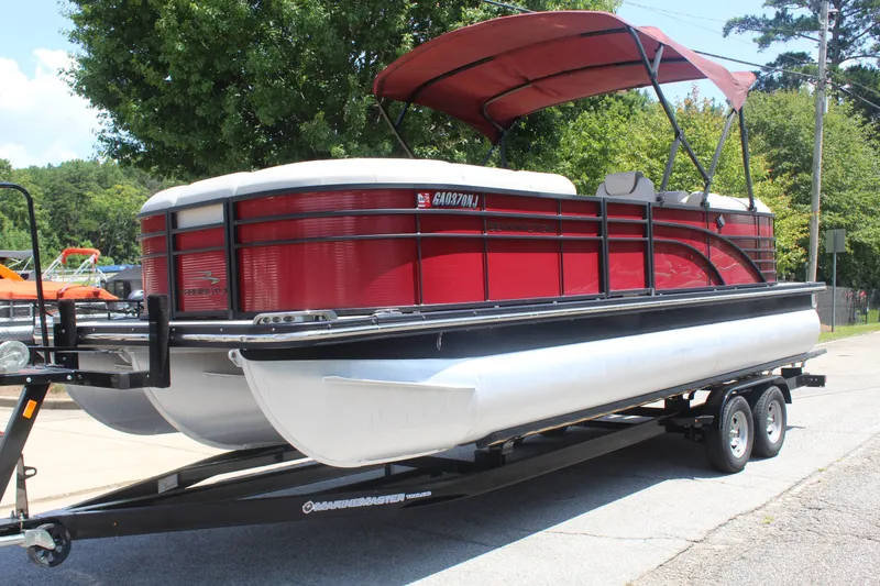 Slide: The Image of A red 2016 Bennington 2250GSR pontoon boat on a trailer, featuring a sun canopy. - 2