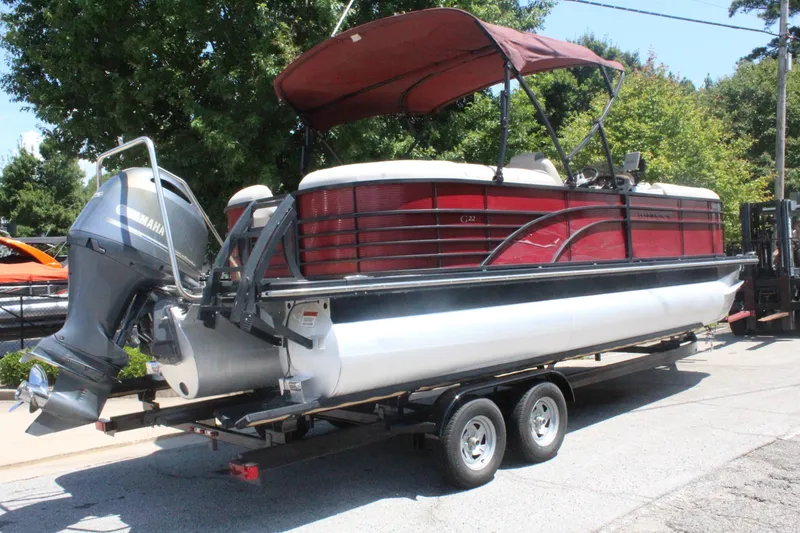 Slide: The Image of A 2016 Bennington 2250GSR pontoon boat on a trailer. It features a red canopy and an outboard motor. - 7