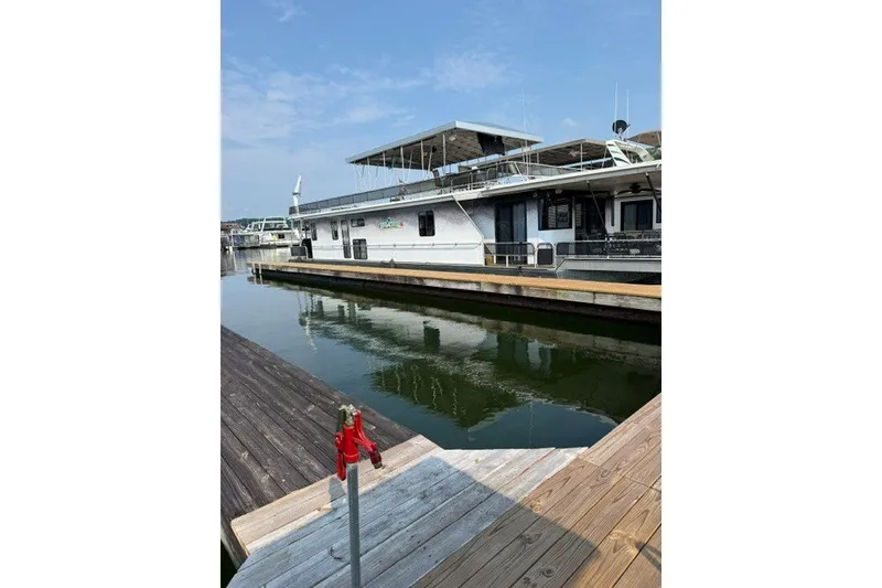 The Image of 1995 Stardust Cruisers 18 x 65 houseboat docked at marina under clear sky. - 0