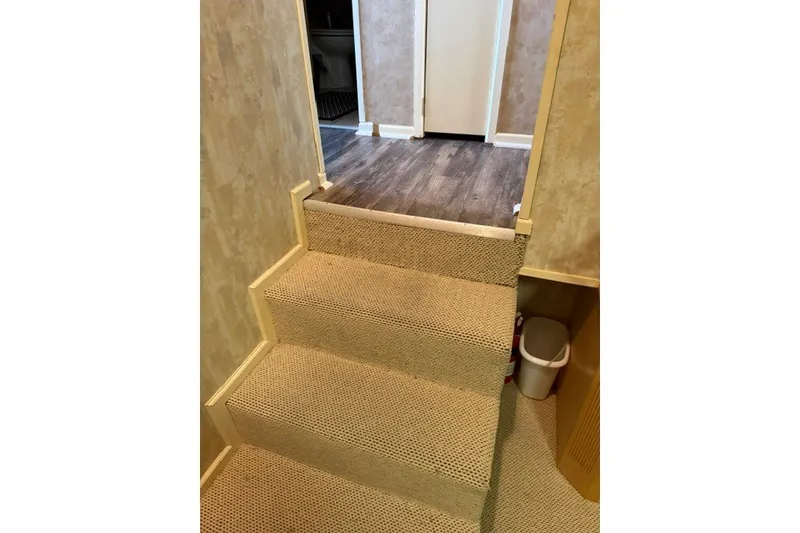Slide: The Image of Carpeted stairs inside a 1995 Stardust Cruisers 18 x 65 houseboat, leading to a wood-floored hallway. - 31