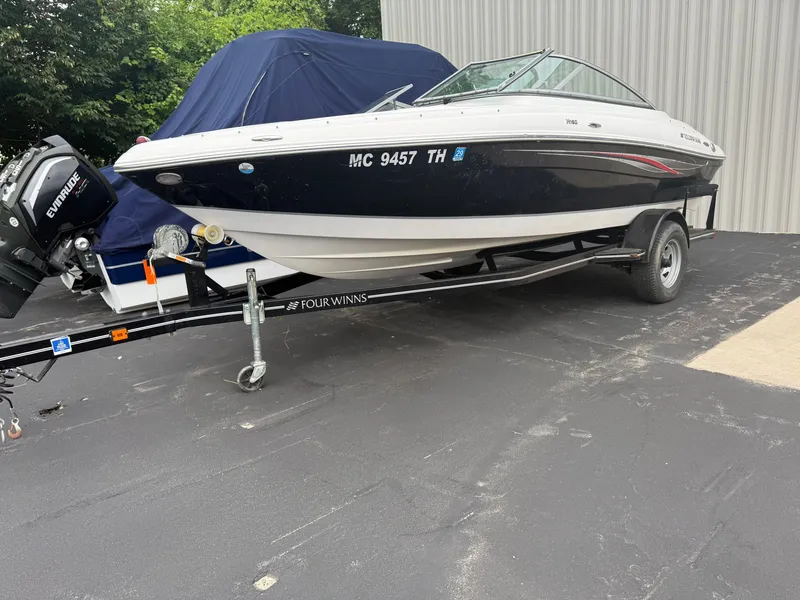 The Image of A 2011 Four Winns 190 Horizon boat on a trailer, parked on a paved lot. - 1