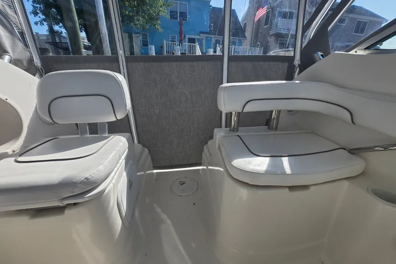 Slide: The Image of Interior seating of a 2004 Wellcraft 252 Coastal boat, featuring white cushioned seats. - 5