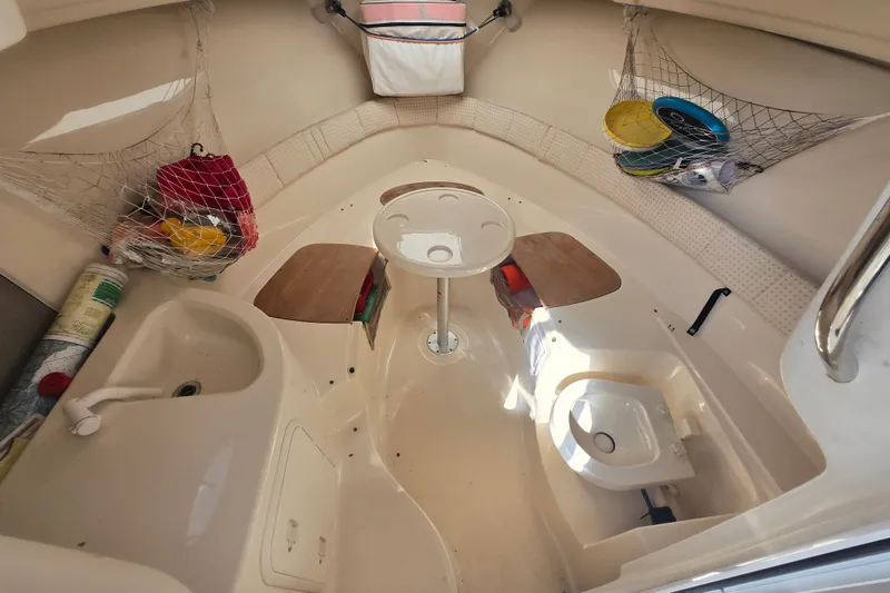 Slide: The Image of 2004 Wellcraft 252 Coastal cabin interior with seating, table, and storage nets. - 1