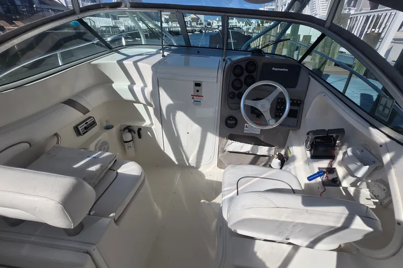 Slide: The Image of 2004 Wellcraft 252 Coastal boat interior with steering wheel and seating, docked at marina. - 2