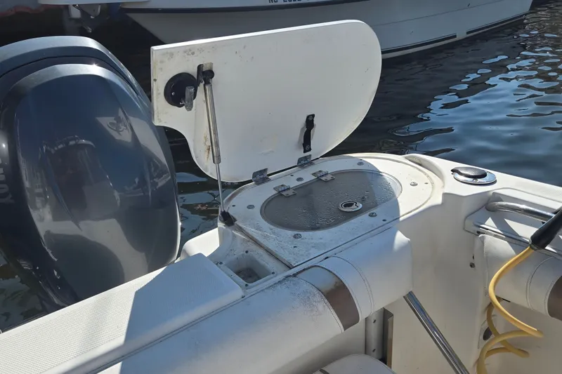 Slide: The Image of 2004 Wellcraft 252 Coastal boat with open storage compartment and visible outboard motor. - 22