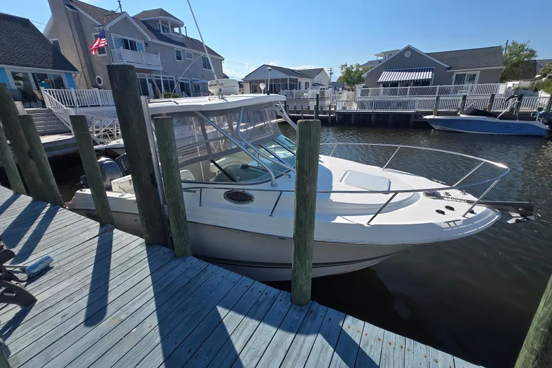 Slide: The Image of 2004 Wellcraft 252 Coastal boat docked at a marina with waterfront homes. - 7