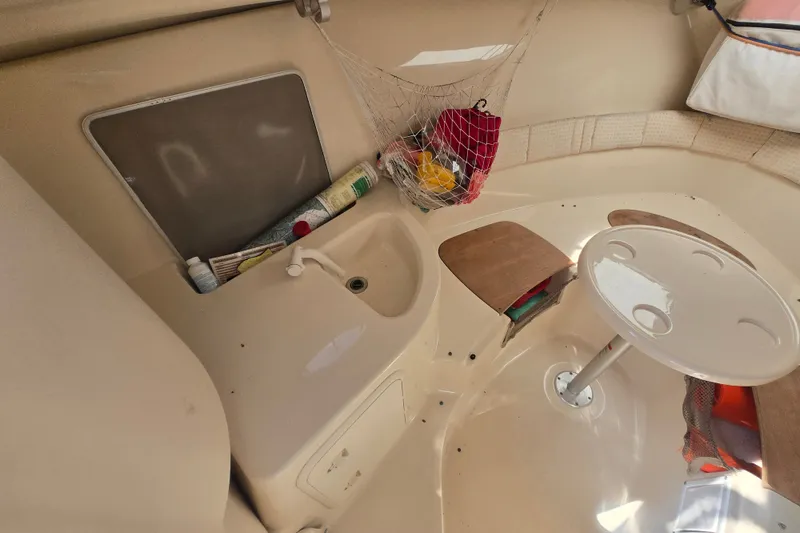 Slide: The Image of 2004 Wellcraft 252 Coastal cabin interior with sink, storage, and table setup. - 14