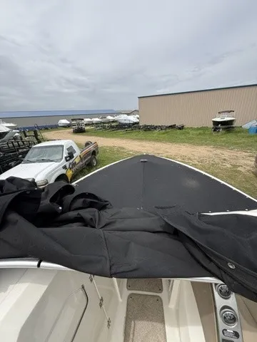 Slide: The Image of 2007 Larson LXi 268 with a black cover, parked in a lot with other boats. - 8