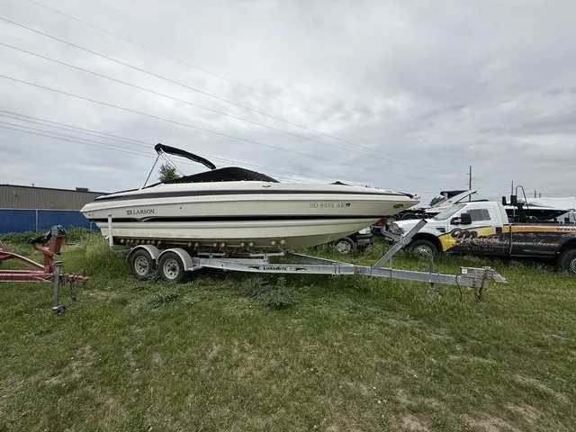Slide: The Image of A white boat with a black canopy on a trailer, parked on grass. - 2