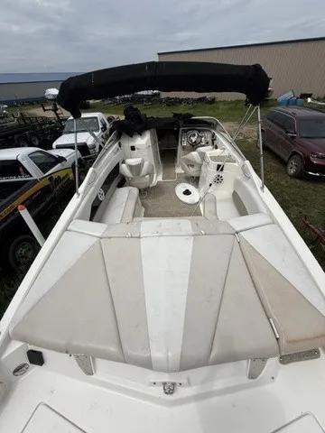 Slide: The Image of A 2007 Larson LXi 268 boat with beige upholstery and black bimini top, parked outdoors. - 32