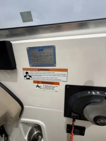 Slide: The Image of Close-up of a 2007 Larson LXi 268 helm area with warning labels and controls. - 16