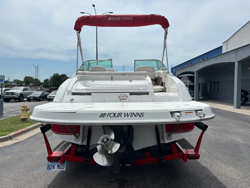 Slide: The Image of A white Four Winns boat with a red sunshade is on a trailer in a parking lot. - 6