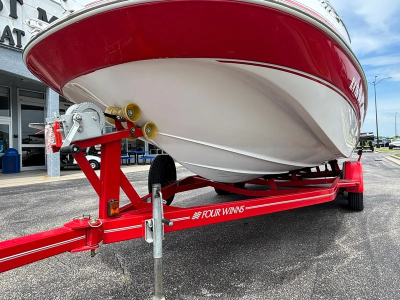 Slide: The Image of A red and white boat, a 2003 Four Winns 214 Fun Ship, sits on a trailer. - 11