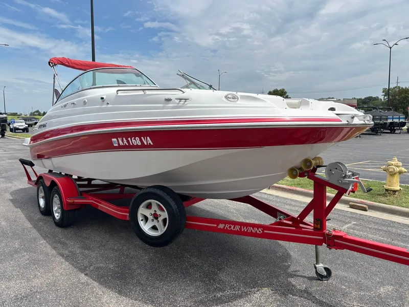 Slide: The Image of A white and red boat on a red trailer. It has a red canopy and is parked in a lot. - 3