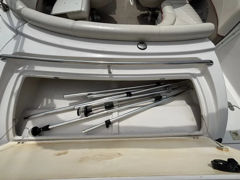 Slide: The Image of An open storage compartment on a 2003 Four Winns 214 Fun Ship with collapsible metal poles. - 15