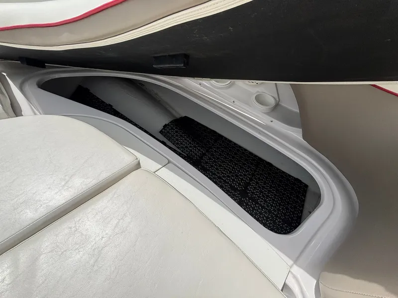 Slide: The Image of An open storage compartment under a white seat on a boat, featuring a black mesh bottom. - 33