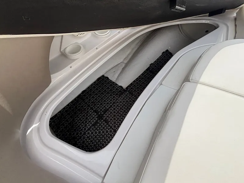 Slide: The Image of An open storage compartment in the boat with black net lining and white upholstery. - 34