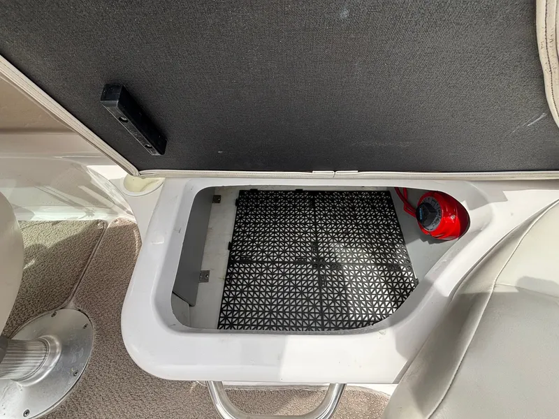 Slide: The Image of An open storage compartment on a boat with a black grid floor and a red fire extinguisher. - 19