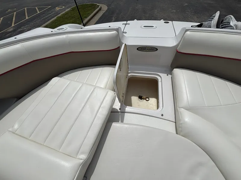 Slide: The Image of The image shows the bow area of a 2003 Four Winns 214 Fun Ship with white cushioned seats and a storage compartment. - 35