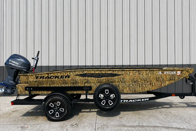 The Image of 2025 Tracker Grizzly 1650 T Prairie Wings Edition boat with camouflage design on trailer. - 0