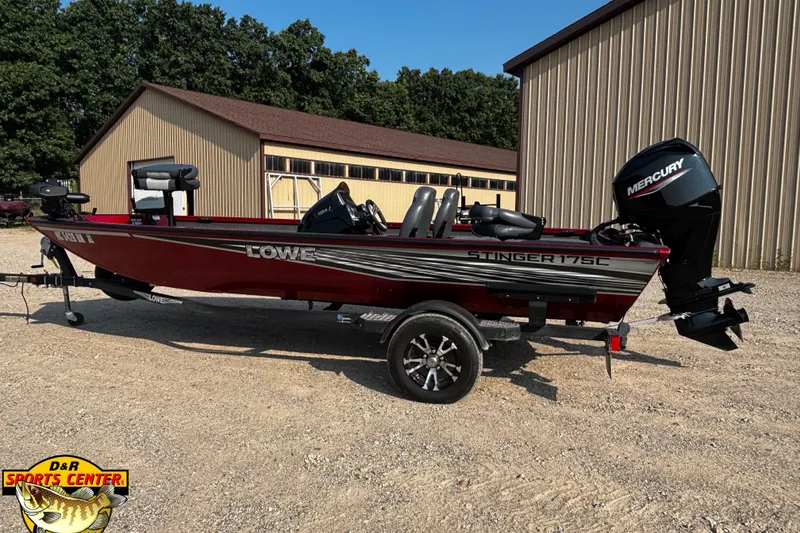 Slide: The Image of 2020 Lowe Stinger 175C fishing boat with Mercury engine, parked outdoors near a building. - 2