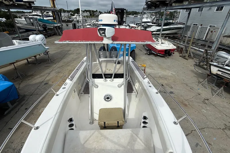 Slide: The Image of 1998 Boston Whaler 23 Outrage boat docked, featuring a red canopy and spacious deck. - 4