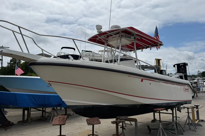 Slide: The Image of 1998 Boston Whaler 23 Outrage boat on stands, with red canopy and American flag. - 2