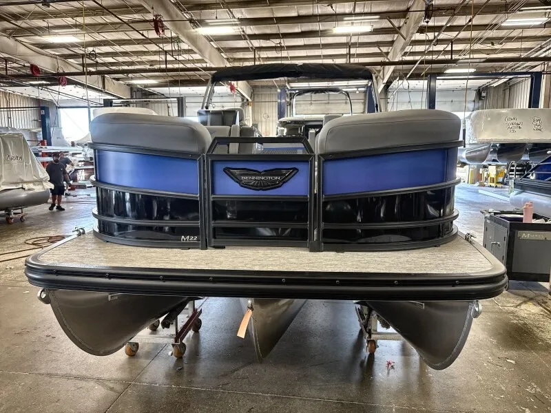 The Image of Bennington 22 M Swingback 2027 in a warehouse, featuring a blue hull and black railing. - 1