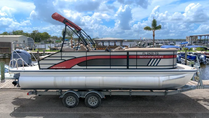 The Image of A 2022 Bennington 22 LSB pontoon boat on a trailer, featuring a red sunshade. - 1