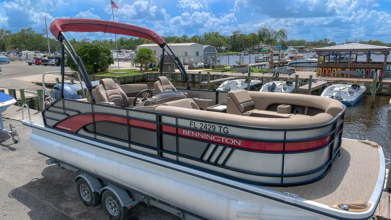 Slide: The Image of 2022 Bennington 22 LSB pontoon boat at dock with red sunshade. - 2