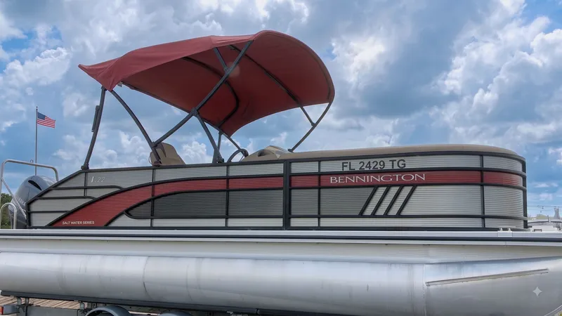 The Image of A 2022 Bennington 22 LSB pontoon boat with a red canopy, on a trailer under a blue sky. - 1