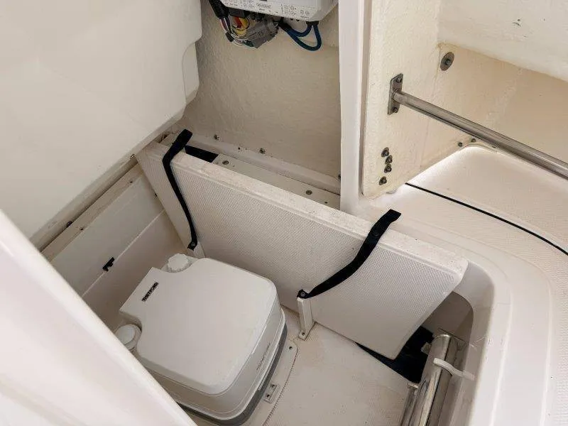 Slide: The Image of The image shows a compact boat toilet with white walls and a folding lid. - 21