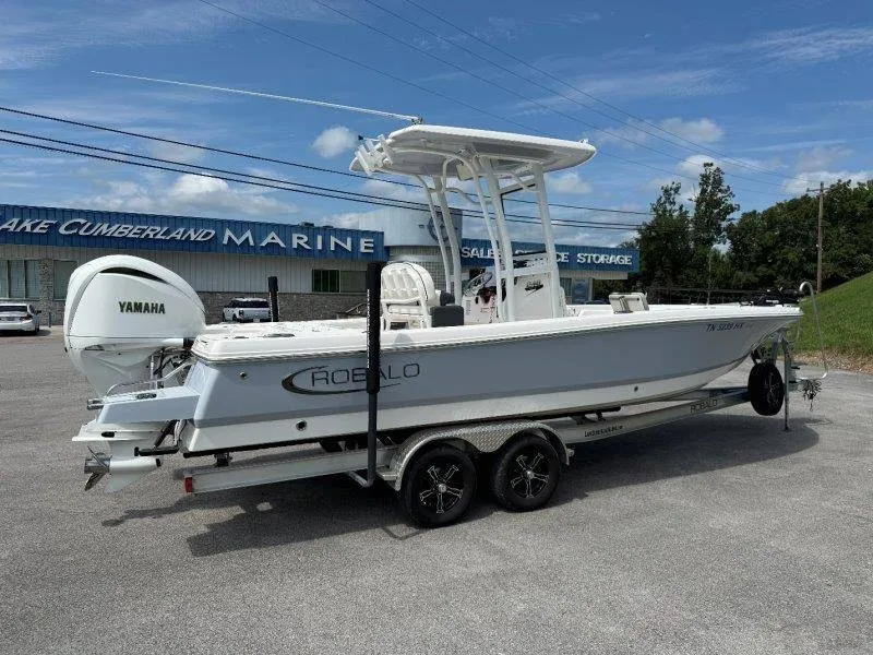 Slide: The Image of A 2023 Robalo 246 Cayman boat on a trailer in front of a building. - 4