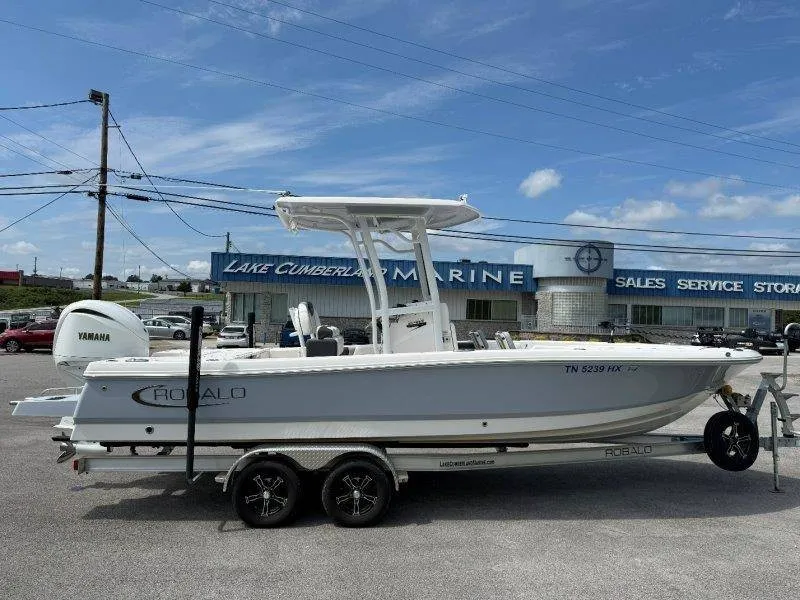 Slide: The Image of 2023 Robalo 246 Cayman on a trailer parked in front of a marine store. - 7