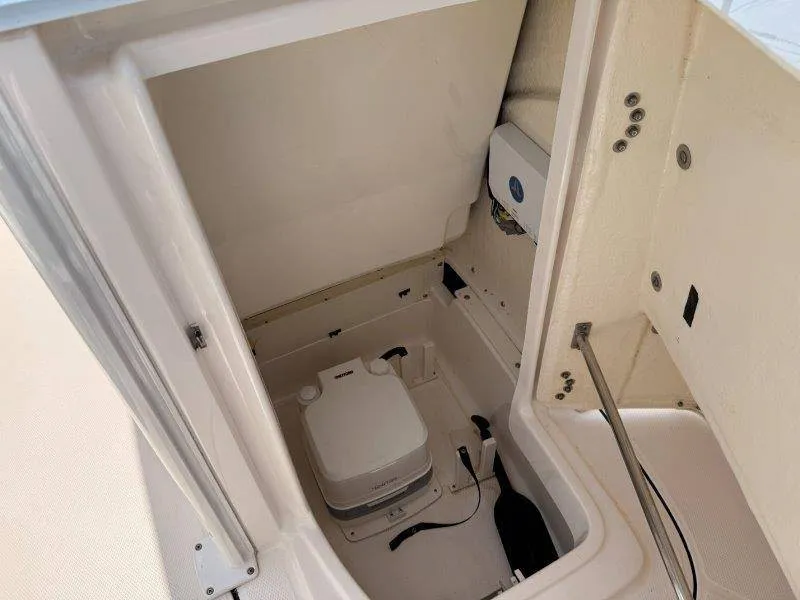 Slide: The Image of The image shows a compact boat toilet in a 2023 Robalo 246 Cayman. - 18