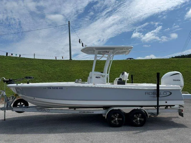 The Image of 2023 Robalo 246 Cayman on a trailer, featuring a T-top and outboard motor. - 1