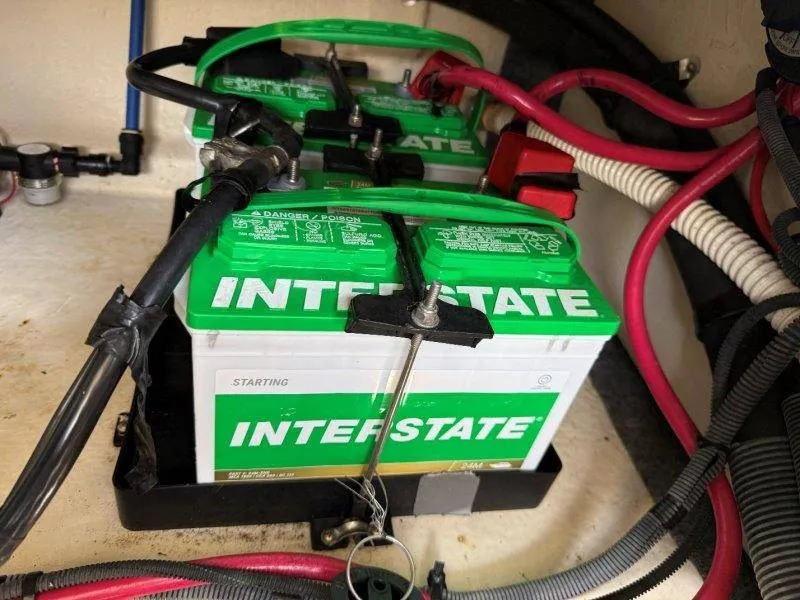 Slide: The Image of Two green Interstate batteries are installed in a boat, surrounded by cables and hoses. - 26