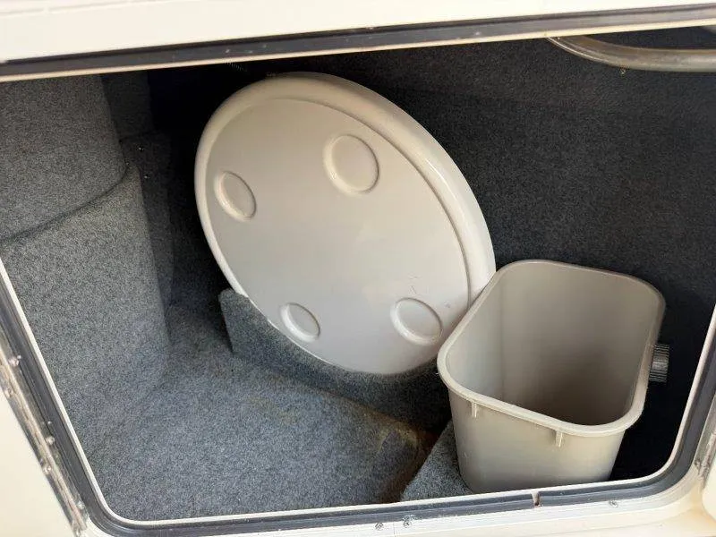 Slide: The Image of A storage compartment inside a boat with a round lid and a trash bin. - 24