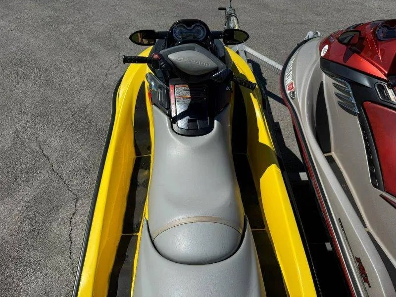 Slide: The Image of Two Sea-Doo jet skis, one yellow and one red, are parked side by side on pavement. - 16