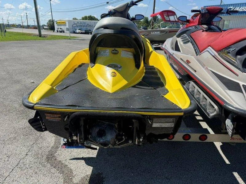 Slide: The Image of Two Sea-Doo jet skis, yellow and red, parked on a trailer outdoors. - 3