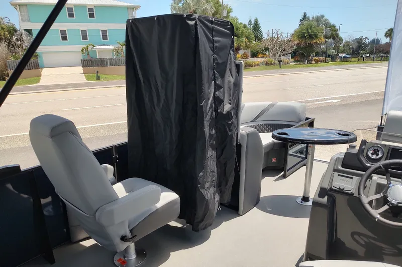 Slide: The Image of 2027 Sylvan X1 ULZ boat interior with seating, table, and steering wheel, near a coastal road. - 11