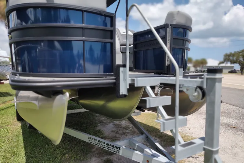 Slide: The Image of 2027 Sylvan X1 ULZ pontoon boat on trailer, sunny day, grassy area. - 4