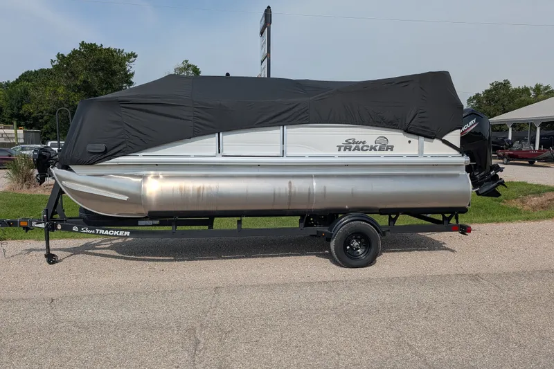 Slide: The Image of 2027 Sun Tracker Party Barge 18 DLX pontoon boat on trailer, covered with black tarp. - 21