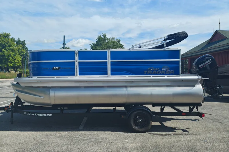 The Image of 2027 Sun Tracker Party Barge 16 DLX pontoon boat on trailer, parked outdoors. - 1