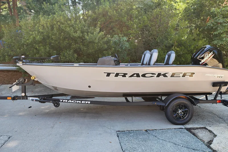 The Image of 2027 Tracker Pro Guide V-16 SC boat on trailer, parked outdoors. - 0