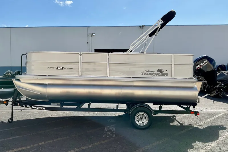 The Image of 2027 Sun Tracker Party Barge 18 DLX pontoon boat on trailer, parked outdoors. - 0