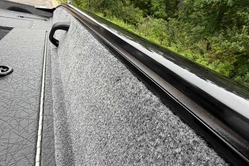Slide: The Image of Interior view of 2027 Tracker Pro Guide V-16 SC boat with textured flooring and lush greenery outside. - 19